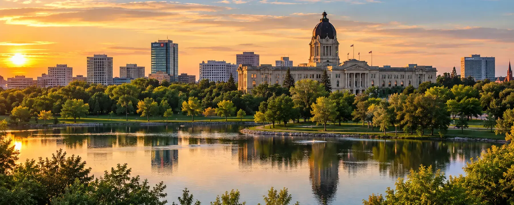 A domed legislature building and city skyline at sunset, reflected in a lake.
